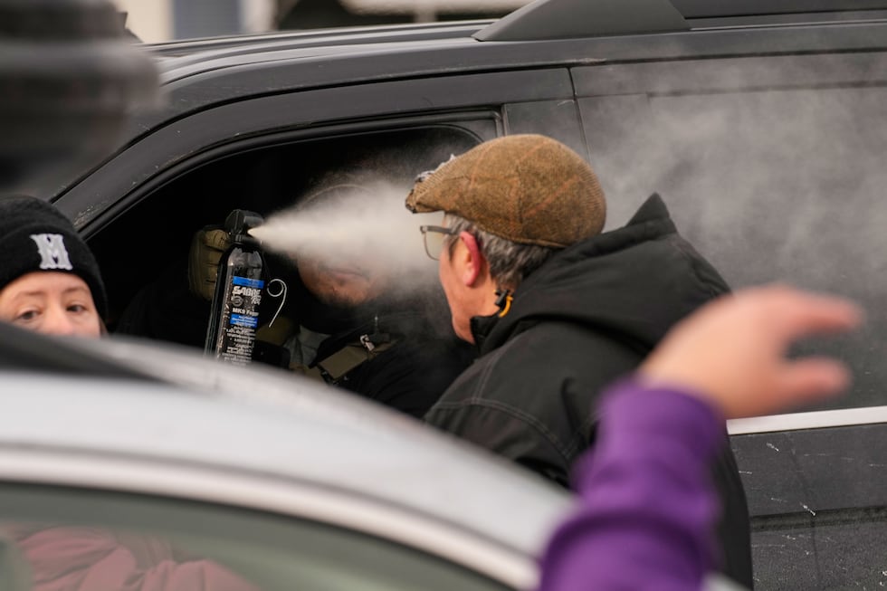 A federal immigration officer deploys pepper spray as officers make an arrest Sunday, Jan. 11,...